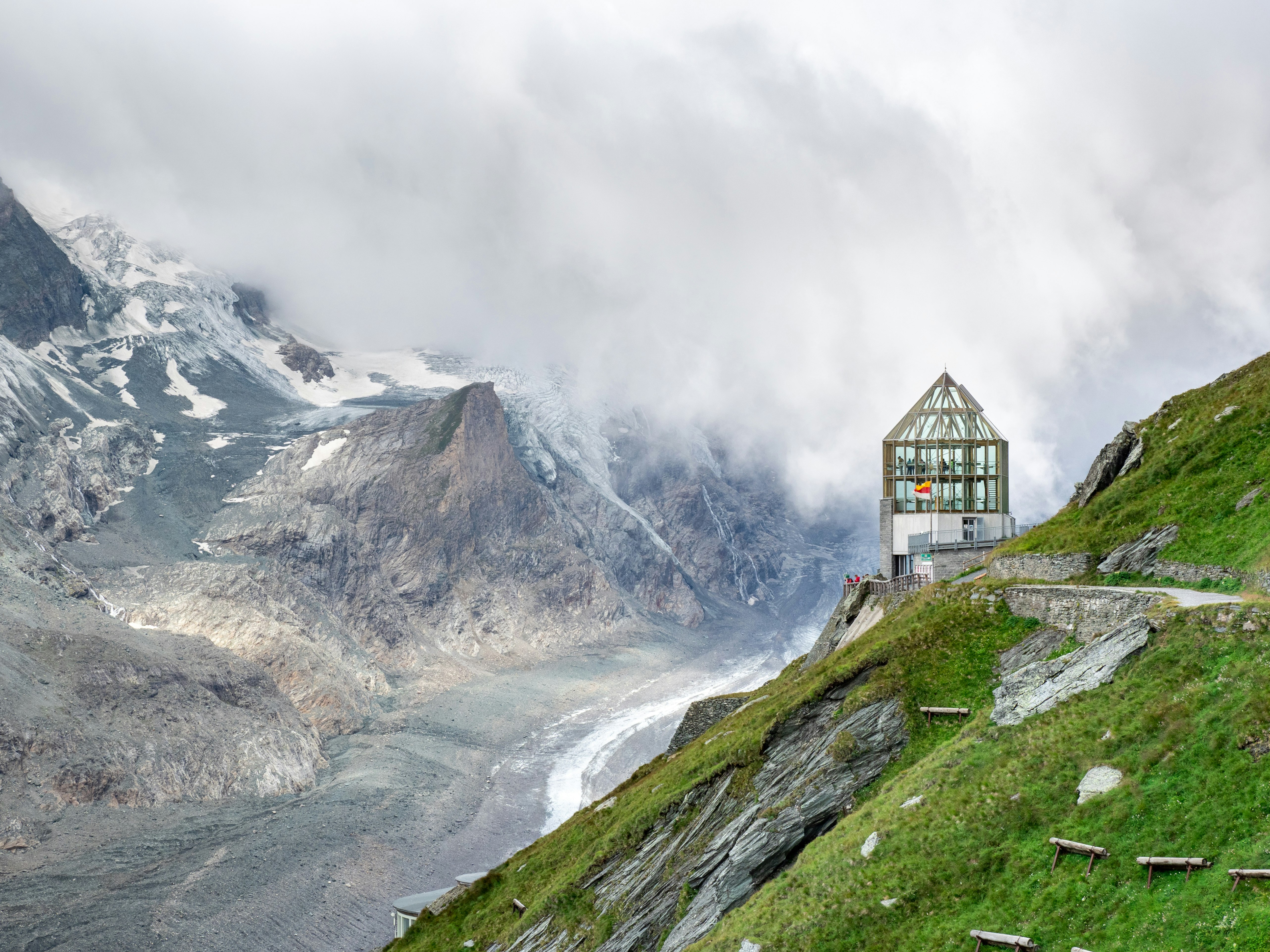 black and white house on green grass field near mountain under white clouds during daytime